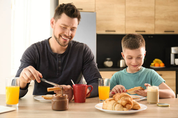 Dad and son having breakfast together in kitchen - Foto, afbeelding