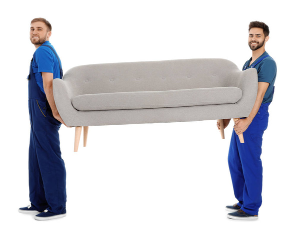 Young workers carrying sofa isolated on white. Moving service - Фото, зображення