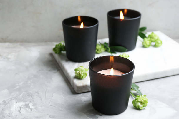 Burning candles with flowers on grey table, space for text - Photo, image