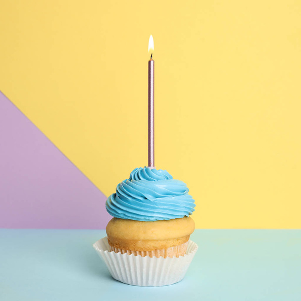 Birthday cupcake with candle on color background - Foto, afbeelding