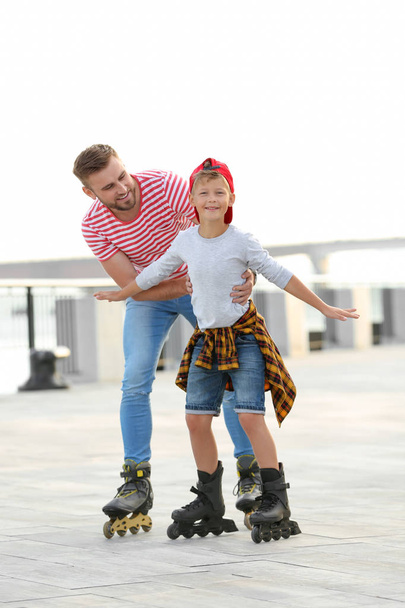 Батько і син катаються на ковзанах на міській вулиці
 - Фото, зображення