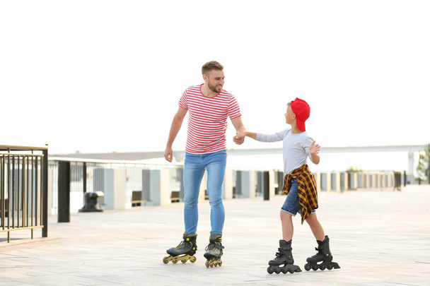 Father and son roller skating on city street - Photo, Image