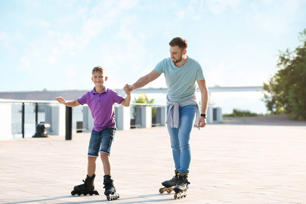 Father and son roller skating on city street - Φωτογραφία, εικόνα
