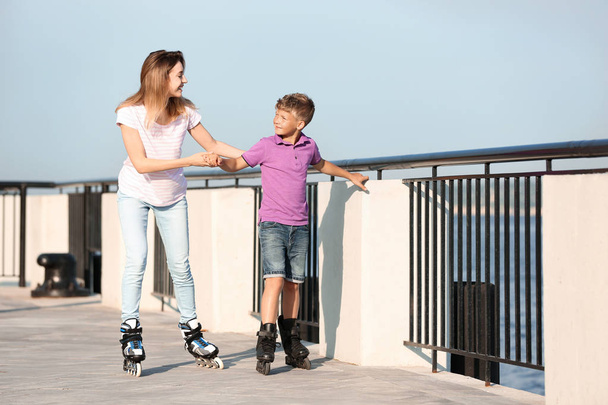 Mother and son roller skating on city street - Foto, imagen
