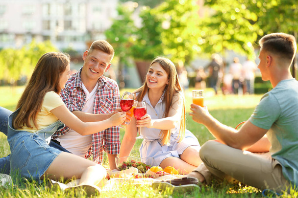 Young people enjoying picnic in park on summer day - Фото, зображення
