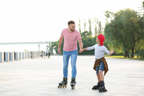 Father and son roller skating on city street - Фото, зображення