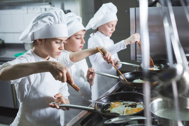 Children cook eggs in the kitchen at the Restaurant. - Photo, Image