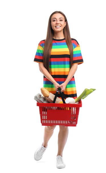 Young woman with shopping basket full of products isolated on white - Foto, Imagen