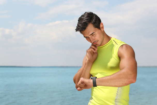 Young man checking pulse after training on beach. Space for text - Foto, imagen
