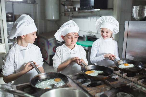 Children cook eggs in the kitchen at the Restaurant. - Zdjęcie, obraz