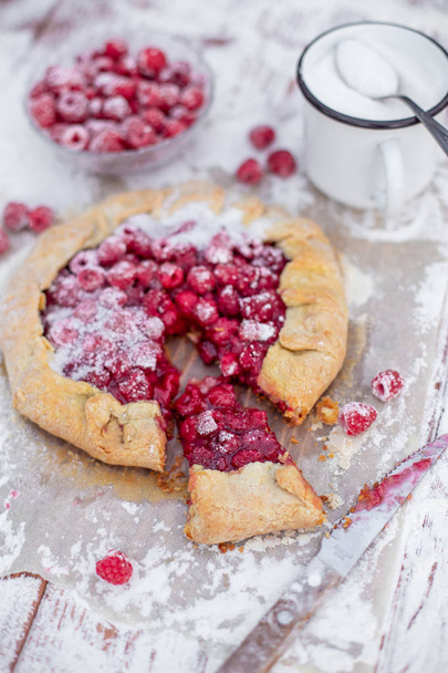 Homemade fruit pie (galette) made with fresh raspberries with powdered sugar on wooden table. Open pie, raspberry tart. Summer berry dessert.  - Fotoğraf, Görsel