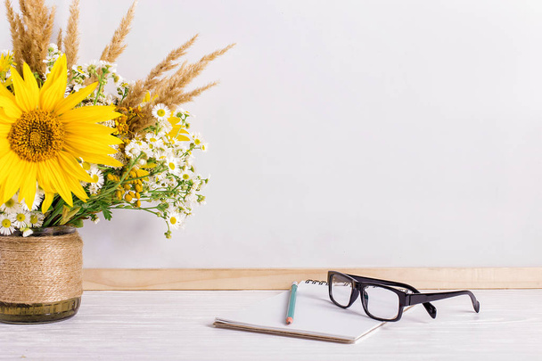 Books, glasses, markers and a bouquet of flowers in a vase on white board background. Concept for teachers day and first September. Copy space. - Φωτογραφία, εικόνα