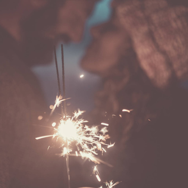 Desfocado pessoas juntas no amor com faíscas de luz de fogo em primeiro plano
  - Foto, Imagem
