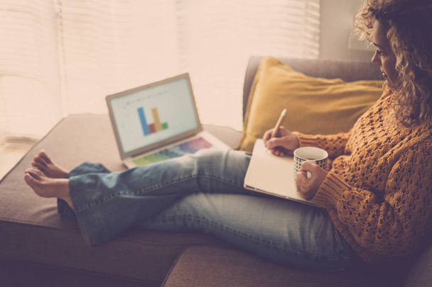 Erwachsene Frau arbeitet zu Hause auf Sofa mit Laptop und Papieren   - Foto, Bild