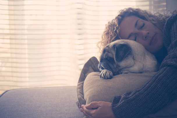 mulher adulta dormindo com melhor amigo pug no sofá em casa
 - Foto, Imagem