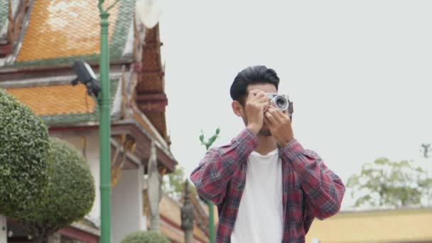 Vonzó fiatal ázsiai férfi turisták utazás és fotózás a templom Thaiföldön. Ázsiai férfi blogger boldog élvezi szabadidős életmód utazás. - Felvétel, videó