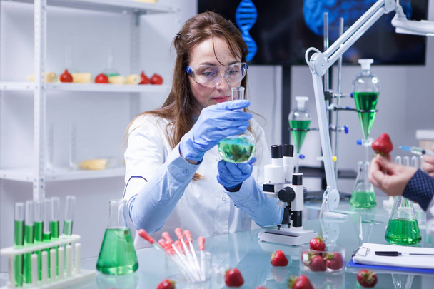 Middelbare leeftijd wetenschapper vrouw dragen bescherming bril in een onderzoek laboratorium - Foto, afbeelding