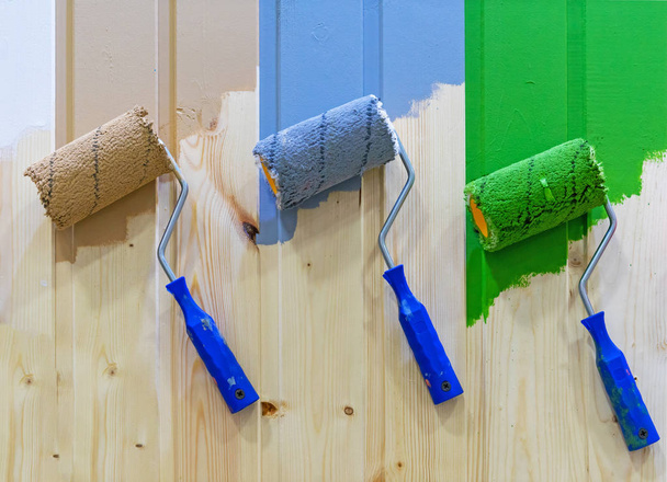Rouleaux de peinture sur un mur en bois. Rouleaux de peinture multicolores
. - Photo, image