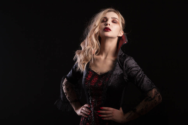 Frau verkleidet wie ein Vampir posiert für den Halloween-Karneval auf dunklem Hintergrund - Foto, Bild