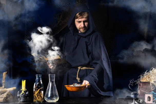 Středověký alchymista dělá kouzelný rituál u stolu v kouřové laboratoři. - Fotografie, Obrázek