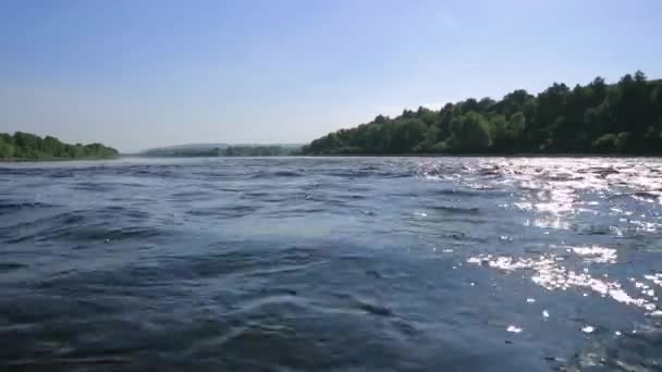 fast flow in the wide shallow river, view on a stones at the bottom through the water. sun glare on water - Video