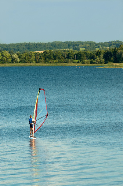 Vesiurheilua. Yksi mies purjehtii järvessä kesäaikaan, tuntematon tuntematon mies purjehtii järvessä, valikoiva keskittyminen
 - Valokuva, kuva