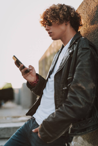 Young man near the wall with smartphone - Фото, зображення