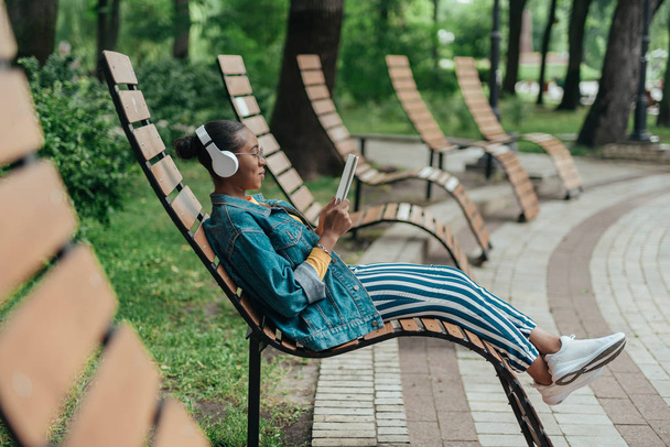 Mujer afroamericana joven está escuchando música al aire libre
 - Foto, imagen