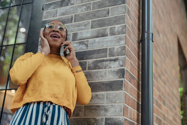 Happy african american female talking at smartphone - Foto, afbeelding