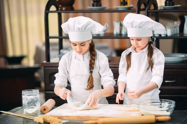 funny girls kids are preparing the dough in the kitchen. - Zdjęcie, obraz