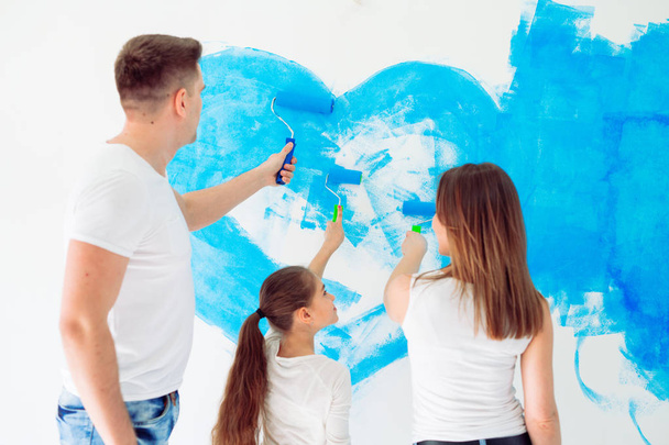 Mother, father and little daughter painting the wall in their new home. - Photo, image