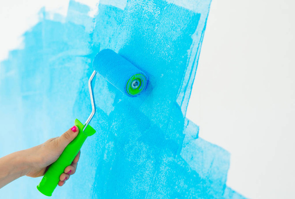 blue color painting wall with roller in hand. - Fotografie, Obrázek