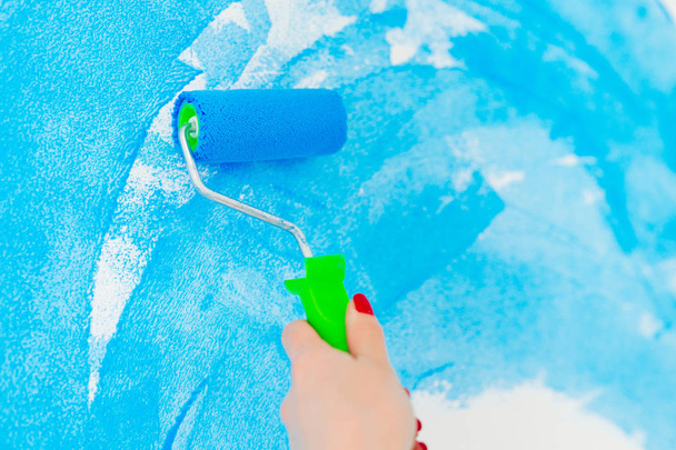 синій колір фарбування стіни з роликом в руці
. - Фото, зображення