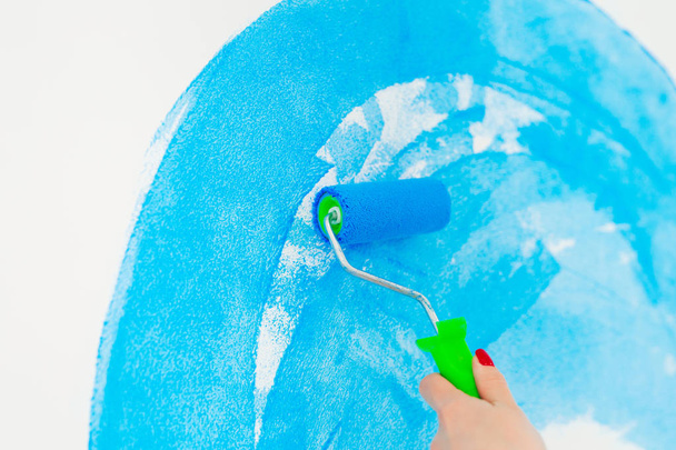 blue color painting wall with roller in hand. - Foto, Imagen