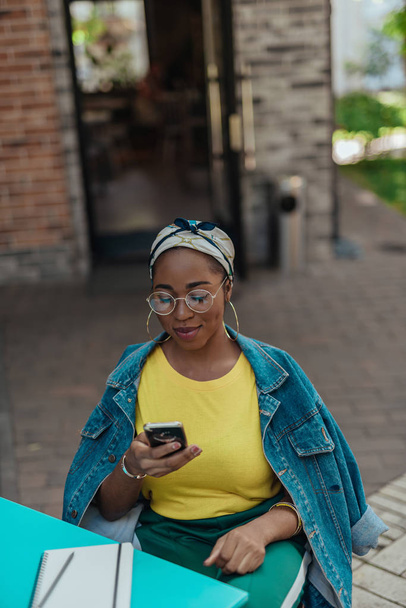 Young afro-american woman using smartphone outside cafe - Photo, Image