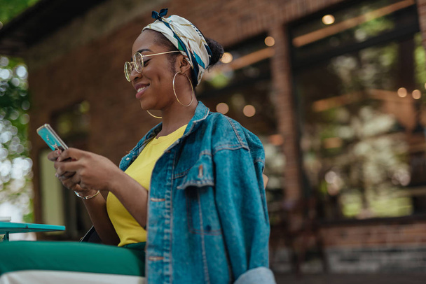 Young adult afro-american woman looking on smartphone - Foto, imagen
