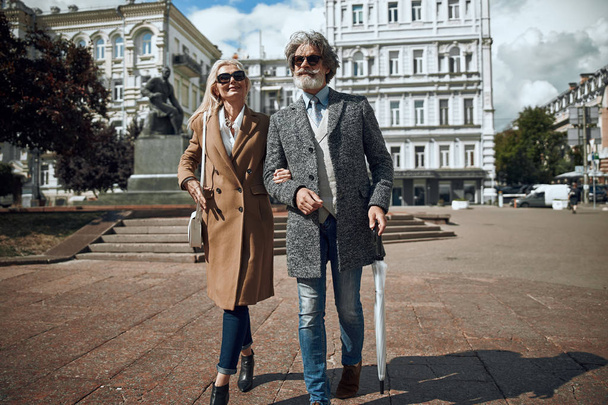 Bearded man with umbrella walking with wife stock photo - Φωτογραφία, εικόνα
