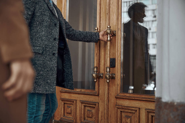 Man in coat opening an old door stock photo - Photo, image