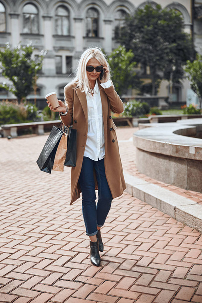Glad adult woman with coffee and smartphone stock photo - Фото, зображення