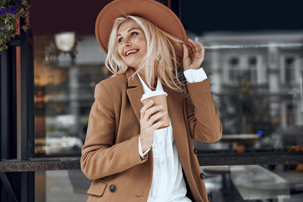 Delighted lady in hat enjoying coffee stock photo - Photo, Image