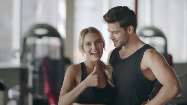 Щаслива пара позує в сучасному спортзалі. Усміхнена жінка показує великі пальці вгору жест
. - Кадри, відео