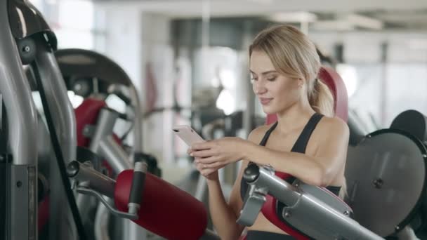 Mujer fitness relajante con teléfono móvil en el gimnasio deportivo
. - Imágenes, Vídeo