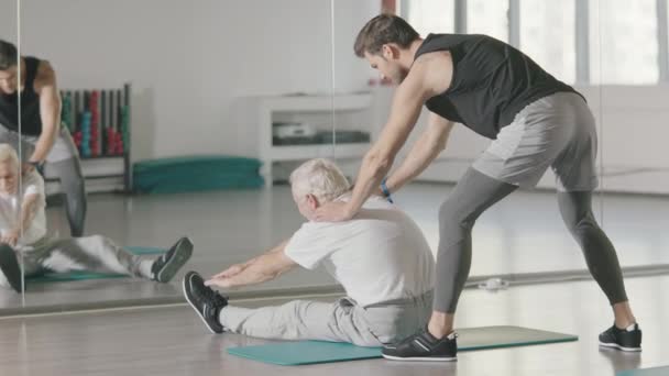 Homme âgé faisant de l'exercice d'étirement devant le miroir dans la salle de gym
. - Séquence, vidéo