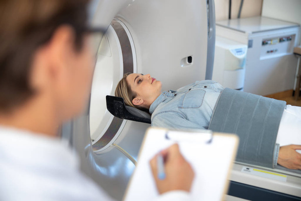 Lady lying on table of CT scan machine - Фото, зображення