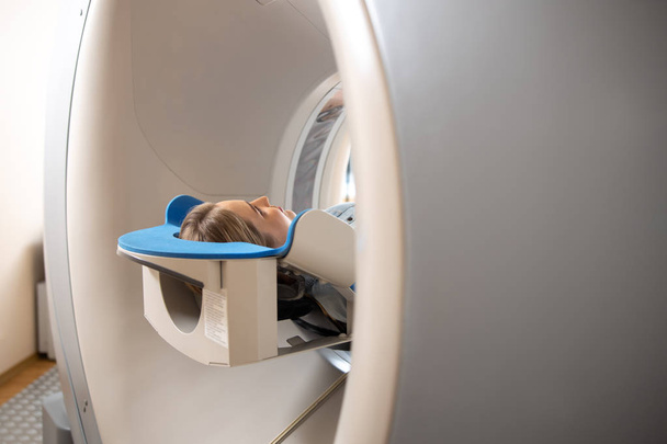 Nuori nainen makaa pöydällä sisällä CT kone
 - Valokuva, kuva