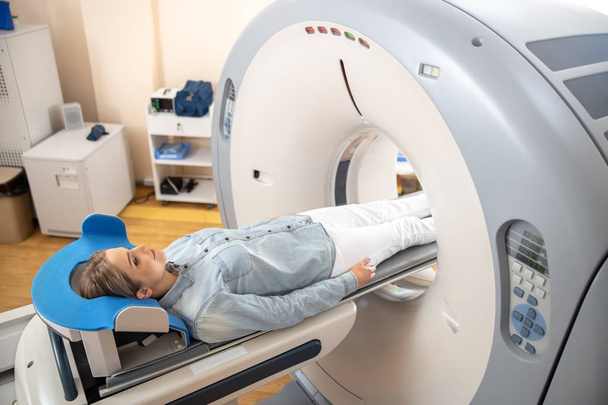 Lady lying on table inside CT machine - Foto, imagen