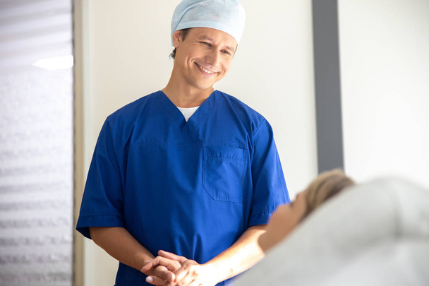 病院の部屋で患者の手を握る喜びの医者 - 写真・画像