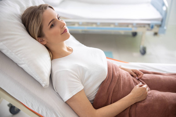 Attractive lady lying in bed at modern clinic - Photo, Image