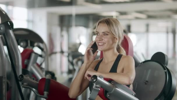 Mooie vrouw met behulp van mobiele telefoon na fitness training. - Video
