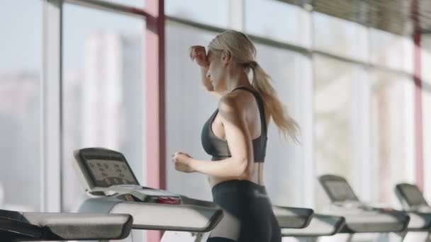 Running woman practicing on treadmill machine in fitness gym. - Filmati, video